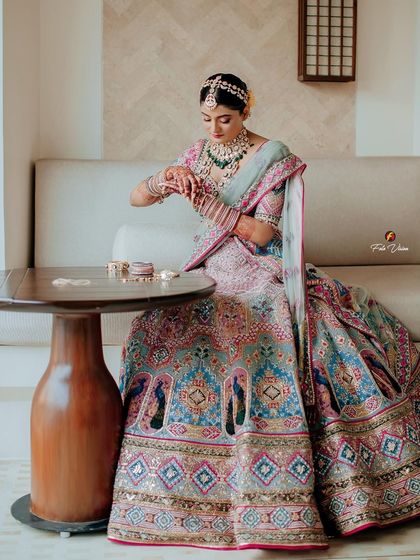 A quiet moment of preparation, with the bride in her stunning pastel lehenga, getting her bangles ready for the ceremony.