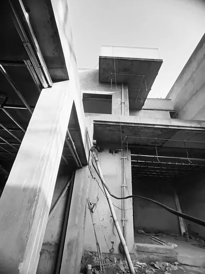 An abstract view of a building's structure from below during construction, emphasizing the raw concrete forms and cantilevered levels.