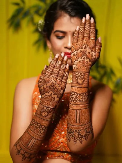 This is a beautiful example of a semi-filled bridal design. It focuses on delicate floral bands and patterns, leaving some skin visible for a lighter, more contemporary feel.