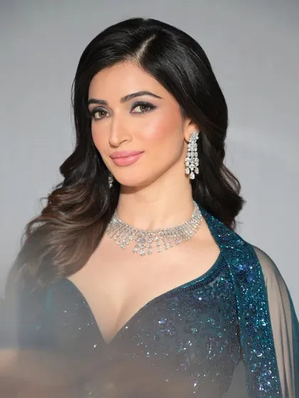 A full view of this glamorous look, featuring a deep blue sequined outfit and sparkling diamond jewelry.