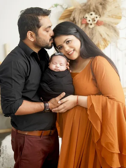 A happy family portrait with their newborn. The parents' loving expressions and the baby's peaceful sleep make this a perfect first family photo in our boho setting.