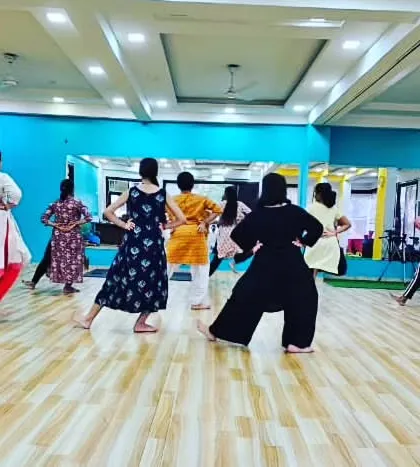 A back view of the class, showing the students mirroring the instructor's movements. This is a fundamental part of learning choreography and technique.