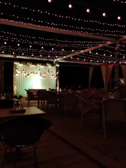 A nighttime view of the restaurant seating area, where the ambiance is set by the warm glow of string lights. Even simple lighting can completely transform a space for an evening celebration.