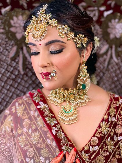 A close-up shot of a bride's makeup, focusing on the glittery eye look and bold red lips. Her hair is styled in an elegant braid adorned with gajra, completing the traditional bridal look.