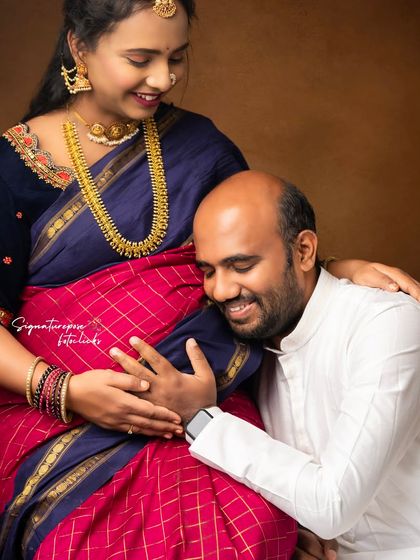 An intimate and heartwarming portrait of a husband listening to the baby bump, a classic pose in traditional Indian attire.