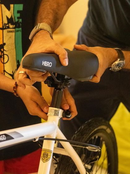 An important part of bike maintenance is adjusting the seat to the right height. Here, I guide a child's hands to show them how to properly loosen and tighten the clamp.