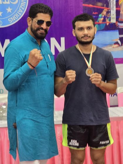 A student poses with an official after receiving his gold medal, a proud moment for him and the academy.