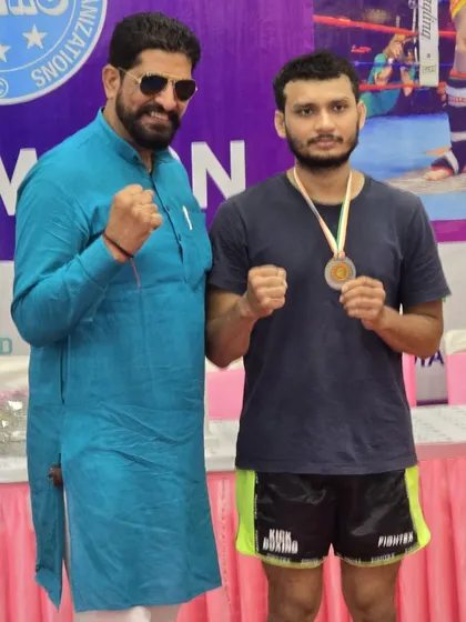 A student poses with an official after receiving his gold medal, a proud moment for him and the academy.