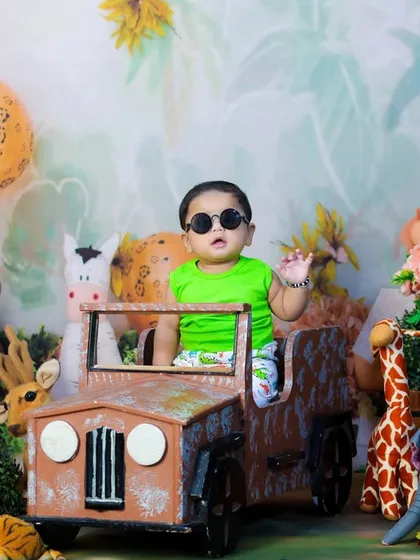 The king of the jungle has arrived. This baby is looking cool in his sunglasses, waving from his safari jeep, surrounded by plush jungle animals.