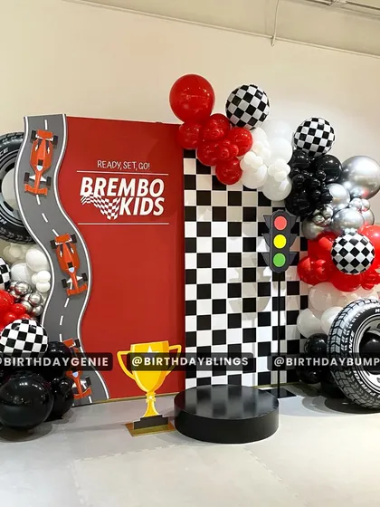 A "Ready, Set, Go!" race car party with a large red backdrop and a checkered flag panel. The trophy and tire props make every guest feel like a winner.