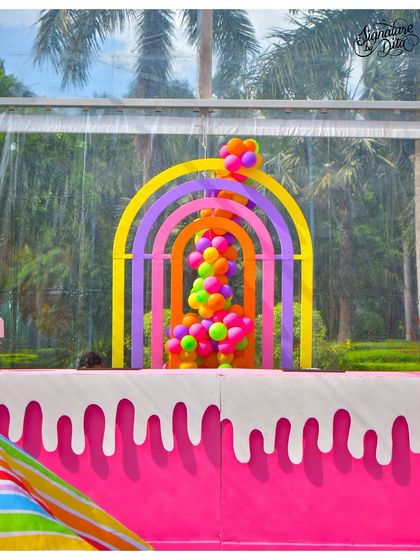 A custom-built rainbow arch with a cascade of colourful balloons pouring out from the centre. This served as a stunning entrance piece for a summer carnival party.