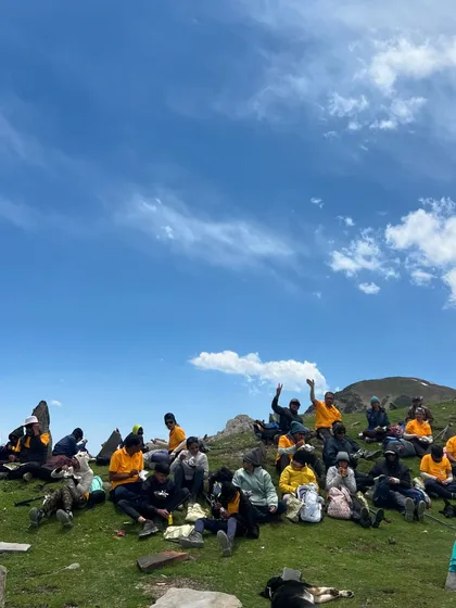 A group of trekkers relaxing on the meadows of Chandrakhani Pass, enjoying the vast open spaces.