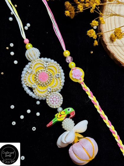 A playful and colorful paired rakhi set with a parrot motif. The Lumba is adorned with a floral design, a small parrot, and shell details, perfect for a fun-loving bhabhi.