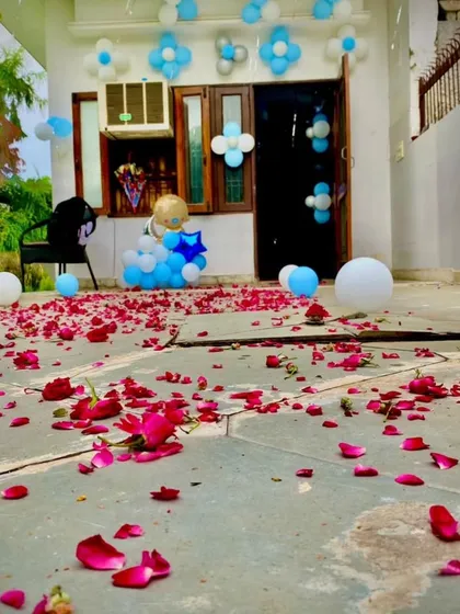 A simple yet heartfelt welcome for a baby boy. The entrance is decorated with blue and white balloons and a path of scattered rose petals, creating a warm and inviting atmosphere.