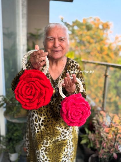 Two stunning red Rose bags with pearl handles, held proudly by Dadi. Perfect for a festive look.