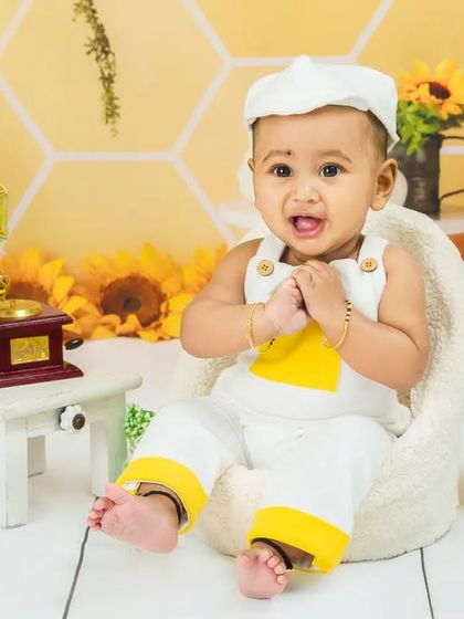 This baby boy is all smiles, looking happy and content in his sunny, sunflower-themed photoshoot.