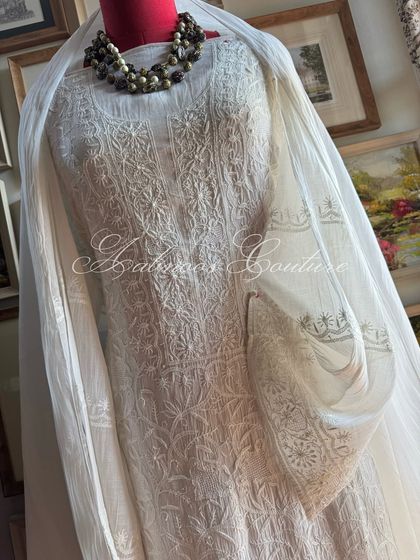 A three-quarter view of the off-white suit, styled with a statement necklace to show its suitability for festive occasions.