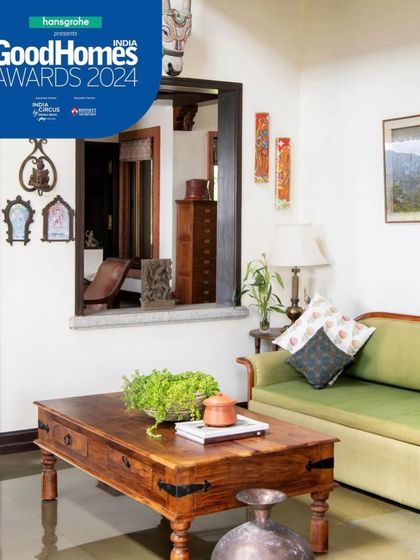 Small, thoughtful details create a sense of calm. An internal window, or 'jharokha,' connects spaces visually, while a simple arrangement of a green sofa and wooden coffee table offers a quiet spot for relaxation.