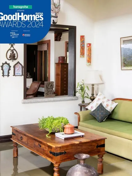 Small, thoughtful details create a sense of calm. An internal window, or 'jharokha,' connects spaces visually, while a simple arrangement of a green sofa and wooden coffee table offers a quiet spot for relaxation.