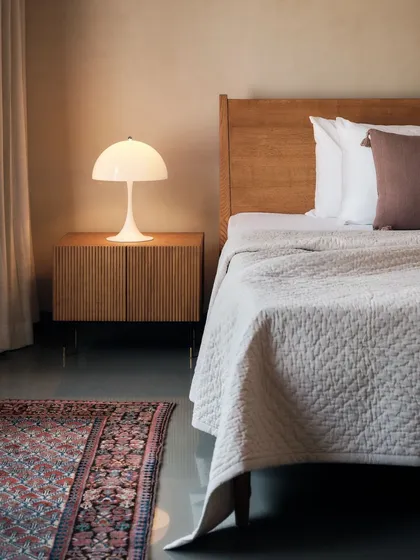 This bedroom corner highlights my love for mixing old and new. A contemporary Louis Poulsen lamp sits beside a 19th-century Kurdish rug, its rare sky-blue indigo dye adding a layer of history and story to this modern farmhouse interior.