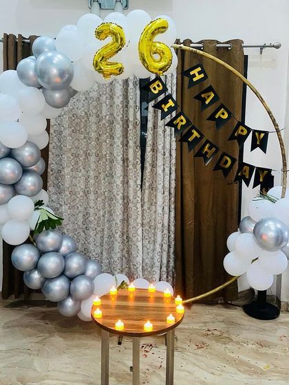 A modern and minimalist take on a birthday backdrop, using a golden hoop frame partially decorated with white and silver balloons.