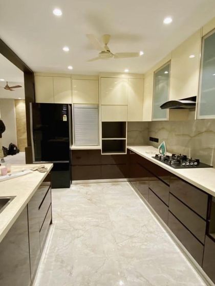 This spacious kitchen in Vasant Kunj uses a beautiful combination of glossy brown and cream cabinets. The design includes an open partition that elegantly separates the kitchen from the dining area.