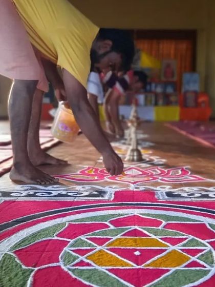 Students participating in Karma Yoga by preparing a rangoli, a sacred geometric design, for a Devi Puja. This selfless service is a way to practice mindfulness and devotion.