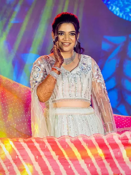 A happy bride on stage, her makeup and hair perfectly styled for her sangeet performance.