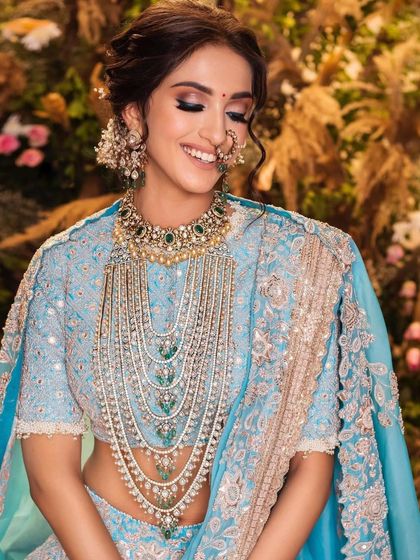 A joyful and candid shot of the bride in the pastel blue lehenga. The makeup looks fresh and radiant, and her smile shows how comfortable and confident she feels.