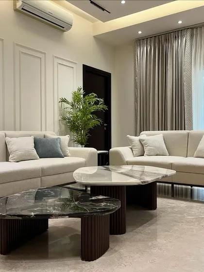 A wider angle of the Sobha International City living room, showing the clean lines of the furniture and the subtle elegance of the wall paneling. Every element is chosen to contribute to a feeling of understated luxury.