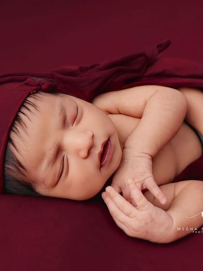This pose, with hands gently placed near the face, looks incredibly peaceful and natural. The matching red hat completes the adorable look.
