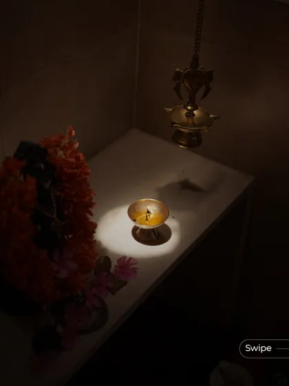 A close-up of a lit diya in the puja nook, its gentle flame creating a serene and spiritual atmosphere. This small detail represents the soul of the home.