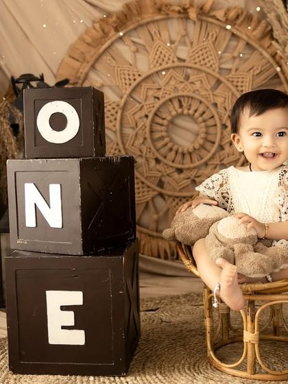 Posing with her teddy bear in a miniature wicker chair, this shot is incredibly sweet. The 'ONE' blocks clearly mark the special first birthday milestone.
