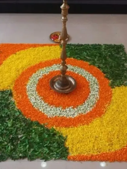 A square floral rangoli with a traditional brass lamp (diya) in the center. This design is perfect for pujas, festivals like Diwali, or housewarming ceremonies.