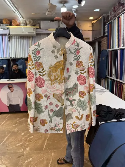 This is a special custom piece we created based on a client's unique design. The off-white Jodhpuri jacket features detailed, multi-colored floral and tiger embroidery, showing how we can bring any design idea to life.