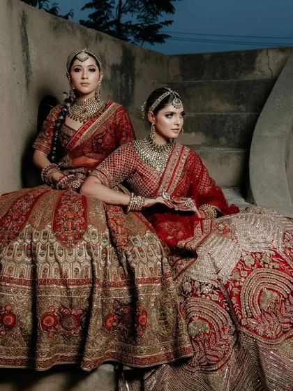 A high-fashion, editorial shot of two brides in traditional red, showcasing my campaign work.