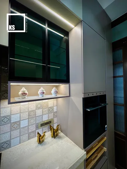 An open niche with accent lighting provides a perfect spot for decorative items, adding a personal touch to the kitchen. The integrated oven is placed at an ergonomic height for ease of use.