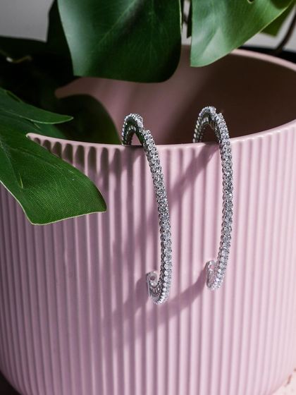 A simple yet effective shot. Placing these diamond hoop earrings inside a pink ceramic pot with a monstera leaf adds a touch of modern, chic, and natural style.