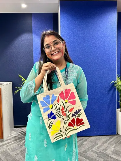 The joy of creating something you can use every day! A participant proudly shows off the beautiful floral design she painted on her tote bag during one of our DIY workshops.