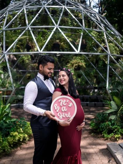 And for this couple, it's a girl! The same versatile maroon fitted gown works perfectly for any announcement, creating a sleek and modern silhouette against a lush garden backdrop.