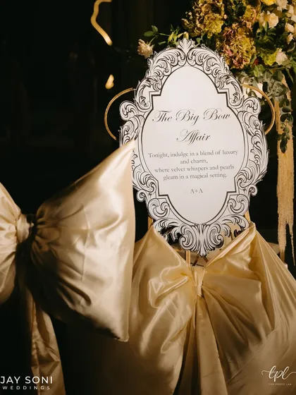 The "Big Bow Affair" welcome sign, featuring an ornate, vintage-style frame and surrounded by large, luxurious satin bows, perfectly introducing the theme of the evening.