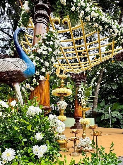 A closer look at the details of our peacock-themed mandap. The combination of carved wood, brass lamps, and delicate white flowers creates a look of traditional South Indian grandeur.
