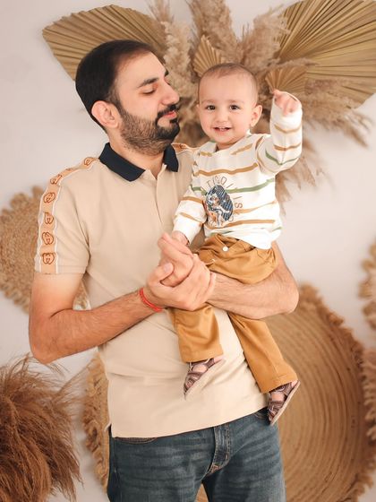 A proud father holds his son, who points up with excitement. This candid interaction during a family studio session captures a moment of discovery and connection.