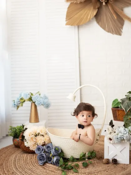 A little boy in a bowtie has fun in a basket during his milestone session. We use simple props to create classic and charming portraits.