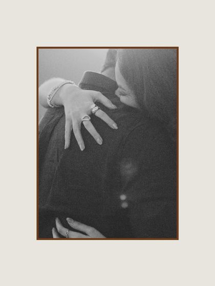 A simple, heartfelt embrace captured in black and white. This close-up on the bride's hand on her partner's back speaks to the trust and comfort they find in each other.