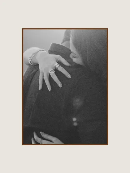 A close-up, black and white shot focusing on the bride's hands as she embraces the groom. This detailed, intimate photo highlights the tenderness and connection in a simple gesture.