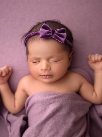 A simple, elegant portrait focusing on this baby girl's sweet face. The purple wrap and matching bow add a lovely pop of color.