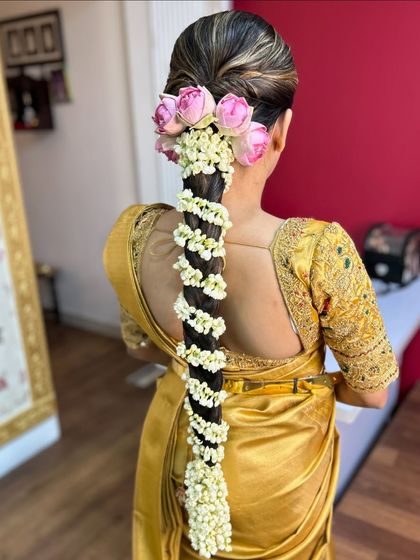 A side profile of the bride, highlighting the elegant placement of pink roses and jasmine on her traditional braid.