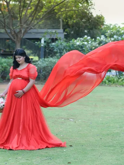 Our flowing gowns are made for creating drama and movement. This shot captures the beauty of our red chiffon gown as it catches the breeze during an outdoor park session, making for a truly dynamic portrait.