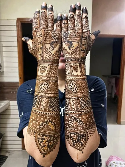 The back of the hands for a full bridal mehendi. This design continues the theme from the front with peacocks and dense, traditional filler patterns.